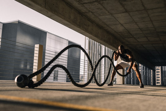 man exercising with battle ropes outdoors