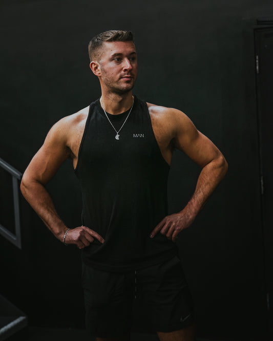 a man in a black tank top is standing with his hands on his hips